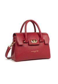 Sac à main en cuir rouge à texture granuleuse avec poignées doubles, bandoulière détachable, quincaillerie dorée et logo embossé à l'avant. Design compact et carré.
