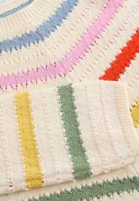 Gros plan d’un tissu tricoté coloré avec des rayures horizontales en bleu, rose, rouge, jaune et vert sur fond crème.