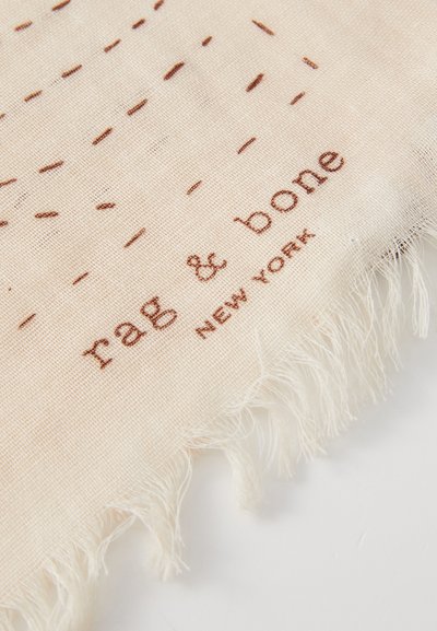 Cremefarbener Schal mit strukturiertem Muster und gesteppten braunen Linien. Die Kanten sind fransig. Enthält "rag & bone" und "NEW YORK" in Brauntönen bedruckt.