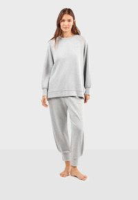 Grijze sweatpants en bijpassende sweatshirt, met een relaxte pasvorm, ribbelmanchetten en een zachte textuur. De broek heeft taps toelopende enkels en een elastische tailleband.