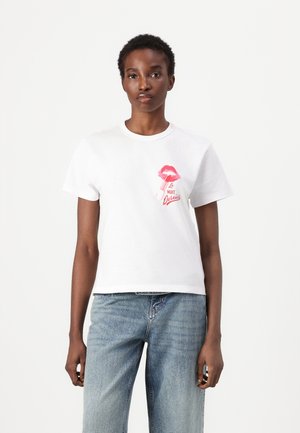 White cotton t-shirt featuring a pink lips graphic and text "Le Nuit Derniers" on the left side, with a relaxed fit and short sleeves.