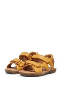 Žluté sandály vyrobené z kůže s otevřenou špičkou, dvěma nastavitelnými suchými zipy a světlými hnědými gumovými podrážkami. Mají výřezy.