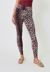 Leopardų rašto leggingai su aukštu juosmeniu, pasižymintys rudos ir kreminės spalvų deriniu, pagaminti iš tamprios, minkštos medžiagos.