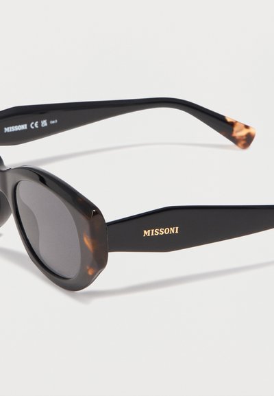 Μαύρα οβάλ γυαλιά ηλίου με λεπτομέρειες από καμηλοπάρδαλη και την λέξη «MISSONI» σε χρυσά γράμματα στο πλευρικό μπράτσο, εμφανίζονται σε λευκό φόντο.