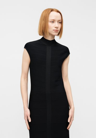 Μαύρο φόρεμα bodycon με ψηλό λαιμό και κοντά μανίκια, με κάθετη ριγωτή υφή και κεντρική λωρίδα. Ομαλό ύφασμα.