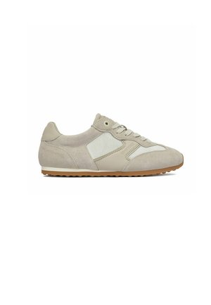 Scarpa da ginnastica beige e bianca dal profilo basso con pannelli in suede e mesh, chiusura con lacci e suola in gomma, vista laterale su sfondo bianco.