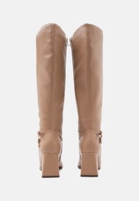 Botas de cuero hasta la rodilla en un tono marrón claro con un acabado texturizado. Cuentan con un tacón cuadrado y cierres de cremallera en la parte posterior.