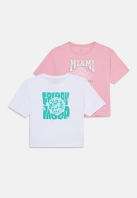Dvě trička s krátkým rukávem: jedno bílé s tyrkysovým grafickým prvkem "FRIDAY MOOD" a globem; druhé růžové s textem "MIAMI BEACH" v krémové barvě. Obě jsou z bavlny.
