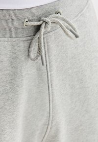 Szare bawełniane spodnie dresowe z elastycznym, prążkowanym pasem z regulowanym sznurkiem oraz gładką tkaniną o subtelnej fakturze i detalach przeszyć.