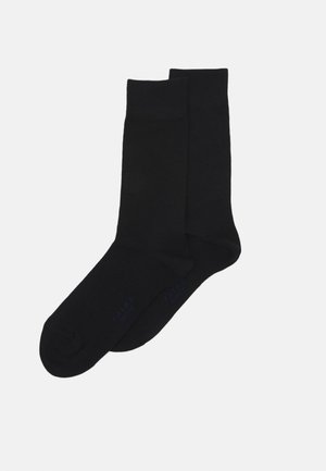 Schwarze Crew-Socken aus einem glatten Material, mit einem gerippten Bündchen und dezentem Markenschriftzug in Blau in der Nähe der Zehen.