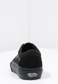 Baskets en cuir suede noir et toile avec un profil bas, dotées d'une semelle en caoutchouc et d'une étiquette de logo au talon. Design simple avec des accents minimalistes.