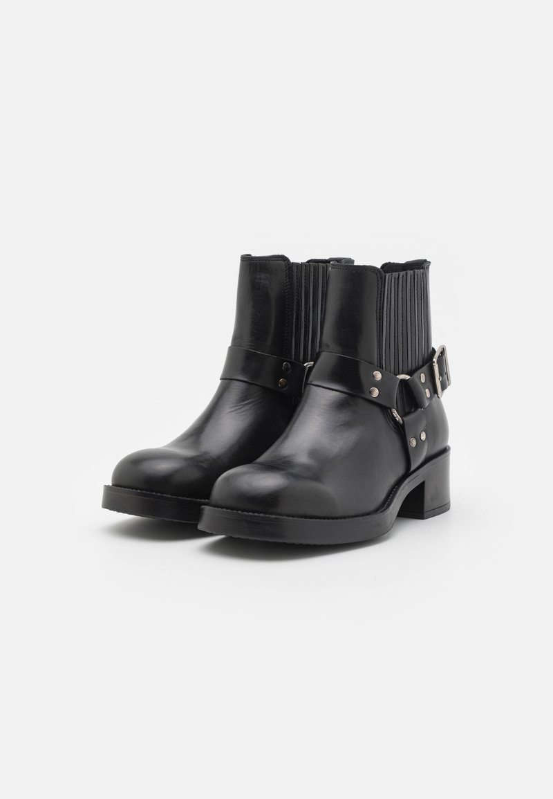 Schwarze Lederstiefeletten mit rippierten elastischen Seiten, metallischen Schnallenakzenten und einem niedrigen Blockabsatz. Glatte Textur, runde Zehenform.