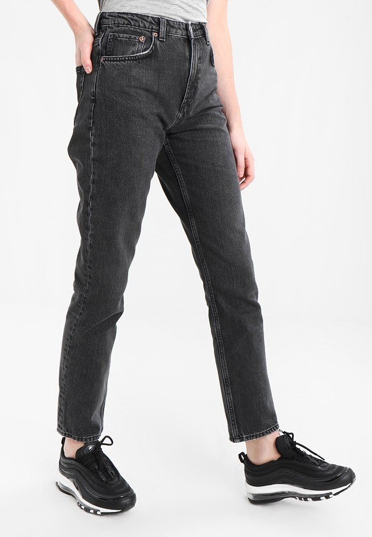 Zwarte denim jeans met een hoge taille, rechte pijpen en voorzakken. Te combineren met zwarte sportschoenen met witte zolen.