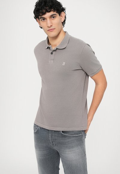 Γκρι πόλο πουκάμισο με γιακά, δύο μαύρα κουμπιά και ένα μικρό λογότυπο. Συνδυασμένο με γκρι τζιν denim, απεικονίζεται σε ανοιχτό φόντο.