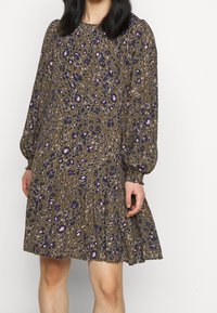 Ruskea kuviollinen mekko, jossa on pitkät puffihihat, violetteja ja vaaleanpunaisia kukkakoristeita sekä kerroksellinen röyhelöhelma. Sileä kangas.