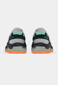 Lette terrengløpesko med grå mesh-overdel, svarte detaljer og en lys oransje såle. Funksjonene inkluderer forsterket hæl og reflekterende detaljer.