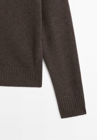 Manche de pull tricoté marron foncé avec poignets et ourlet côtelés sur fond blanc.