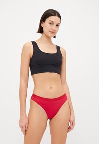 Black crop top with a square neckline and wide straps paired with red bikini briefs. The fabrics appear smooth with minimal detailing.