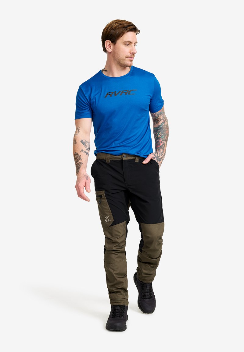 Blå kortärmad t-shirt med svart logotyp, kombinerad med svarta och olivgröna tvåtonspants med sidofickor och slitstark textur.