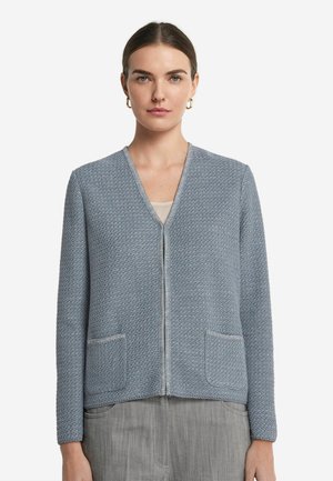 Helles, strukturiertes, hellblaues Strickcardigan mit V-Ausschnitt, langen Ärmeln, Frontreißverschluss und zwei Hüfttaschen. Abgerundet mit kontrastierenden Besätzen.