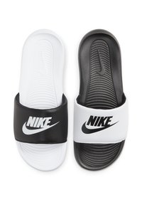 Sorte og hvite Nike flip-flops med teksturerte såler, brede stropper med Nike-logoen, og kontrasterende fargedesign.