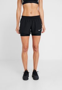 Svarta träningsshorts med elastisk midja och vit Nike-logotyp. Har ett inre kompressionslager för stöd och andningsförmåga.