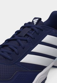 Chaussure de sport bleu marine avec un design à trois bandes blanches, tige en mesh texturé et lacets bleu marine sur un fond clair.