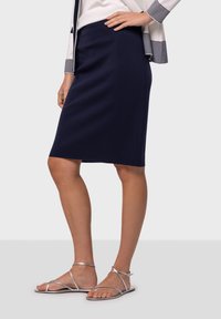 Merenkallon sääriin ulottuva kynähame, joka on valmistettu joustavasta kankaasta, ja siinä on sileä pinta sekä tiivis muotoilu, yhdistettynä hopeisiin nilkkureihin.