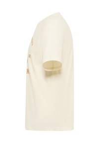 Vue latérale d'un t-shirt à manches courtes uni de couleur blanc cassé avec un texte partiel marron sur le devant, présenté sur un fond blanc.