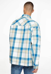 Rutig skjorta med blå och krämfärgade rutor, knäppta ärmslut och klassisk krage. Tillverkad av lätt tyg med en mjuk textur.