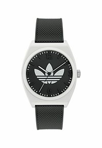 Montre noire avec un bracelet en caoutchouc noir texturé. Boîtier rond en argent, cadran noir arborant le logo Adidas, marquages horaires blancs et aiguilles blanches.