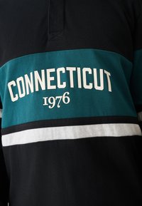 Black, teal, and white striped shirt with "CONNECTICUT 1976" printed in bold white letters across the chest.