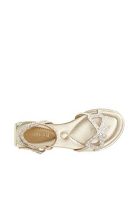 Sandal dorato metallizzato con design a cinturino incrociato, decorato con strass trasparenti, tacco piatto e texture in pelle liscia.