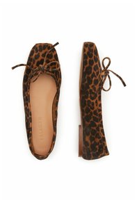 Paire de ballerines à imprimé léopard avec bouts carrés et nœuds noués, une chaussure vue de dessus, l'autre de côté.