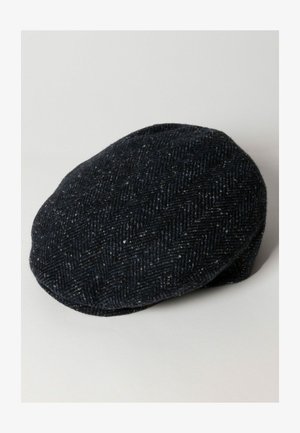Gorra plana de lana en azul oscuro con un patrón de espiga. Forma redondeada, textura suave y un ala ligeramente curvada. Diseño minimalista.