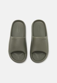 Sandales en caoutchouc vert olive avec un dessus texturé et des aérations latérales, dotées d'un design à bout ouvert arrondi et d'une marque minimaliste.