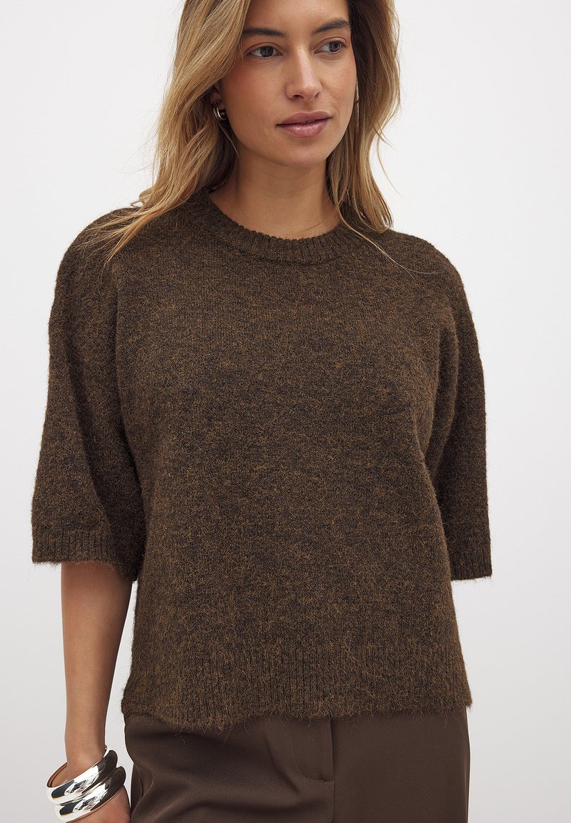 Brauner, strukturierter Strickpullover mit Rundhalsausschnitt und kurzen Ärmeln; hat eine lockere Passform und einen gerippten Saum.