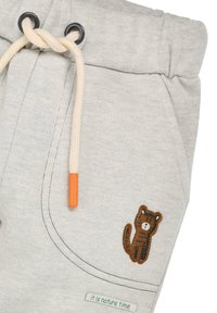 Hellgraue Jogginghose mit Kordelzug, ausgestattet mit einem orangefarbigen Ende, einem braunen Tierpatch und einem "Es ist Naturzeit"-Label.