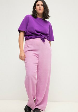 Paarse t-shirt met korte mouwen en een knoop aan de voorkant, gecombineerd met roze wijde broek. De broek heeft een elastische tailleband en een gladde textuur.