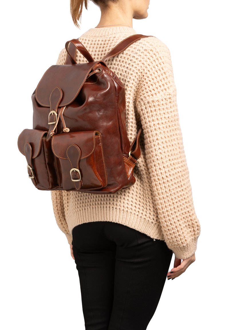 Zaino in pelle marrone con due tasche anteriori, chiusura a patta frontale e spallacci regolabili. Finitura lucida con cuciture a contrasto.
