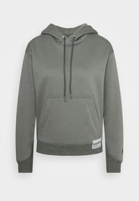 Szary kaptur z kieszenią z przodu, plecioną sznurkiem i ściągaczem u dołu. Posiada teksturowany akcent na dole i na szwach bocznych.