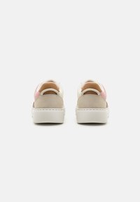 Rückansicht von Sneakers mit einem beigen Obermaterial, rosa Stoffakzenten, weißer Sohle und einer weichen Wildleder-Fersenschlaufe.