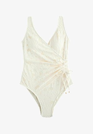 Balts viengabala peldkostīms ar ziedu mežģīņu rakstu, dziļu V-veida izgriezumu un sānu krokām, kas sasietas ar regulējamu auklu.