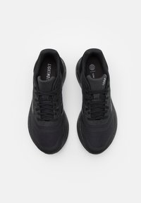 Coppia di scarpe da corsa nere Adidas con tomaia in rete, lacci allacciati e soletti con marchio, viste dall'alto su uno sfondo bianco semplice.