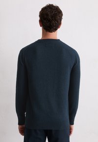 Donkerblauwe gebreide trui met een gestructureerde afwerking. Ronde halslijn, ribgebreide manchetten en zoom, en lange mouwen. Minimalistisch ontwerp, geen zichtbare logo's.