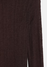 Ribbede, mørkebrune strikkede stoffer med en tekstureret overflade og slidser langs siderne for ekstra detaljer og fleksibilitet.