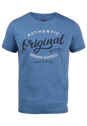 Blå T-skjorte med korte ermer i myk stoff som har et sirkulært typografisk trykk med teksten "Authentic Original Blend Denim Goods."