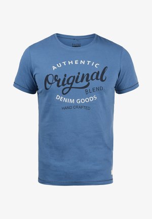 Blå kortærmet T-shirt i blødt stof med et cirkulært typografisk tryk, der viser teksten "Authentic Original Blend Denim Goods."