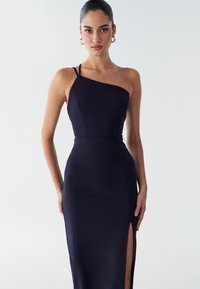 Granatowa dopasowana sukienka z asymetrycznym dekoltem i rozcięciem do uda. Wykonana z gładkiego materiału, ma cienkie ramiączka i eleganckie szwy.