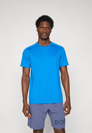 T-shirt de sport bleu à manches courtes avec un col rond et un petit logo sur la poitrine, associé à un short gris avec un design de texte audacieux.